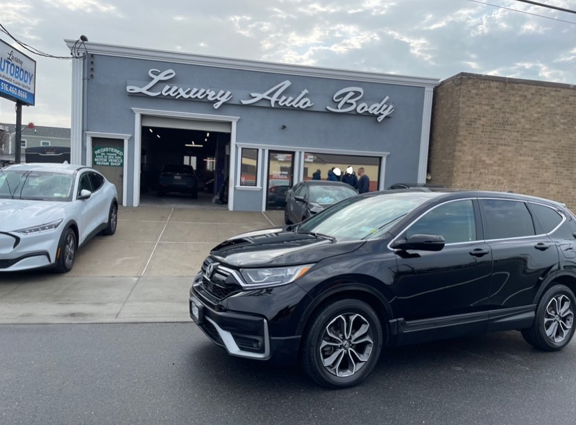 Black Honda CR-V after front fender repair outside Luxury Auto Body