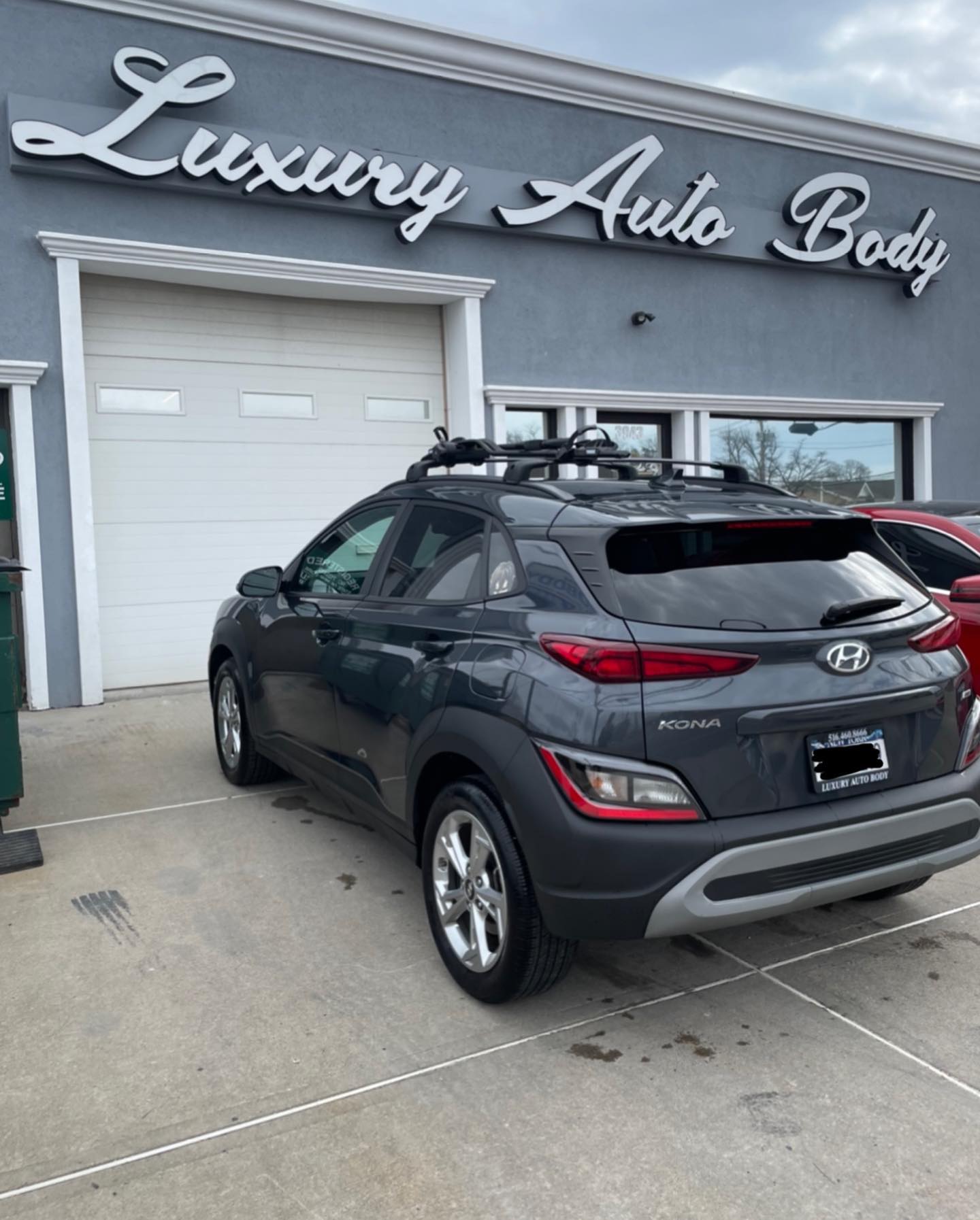 Hyundai Kona after rear side repair in front of Luxury Auto Body