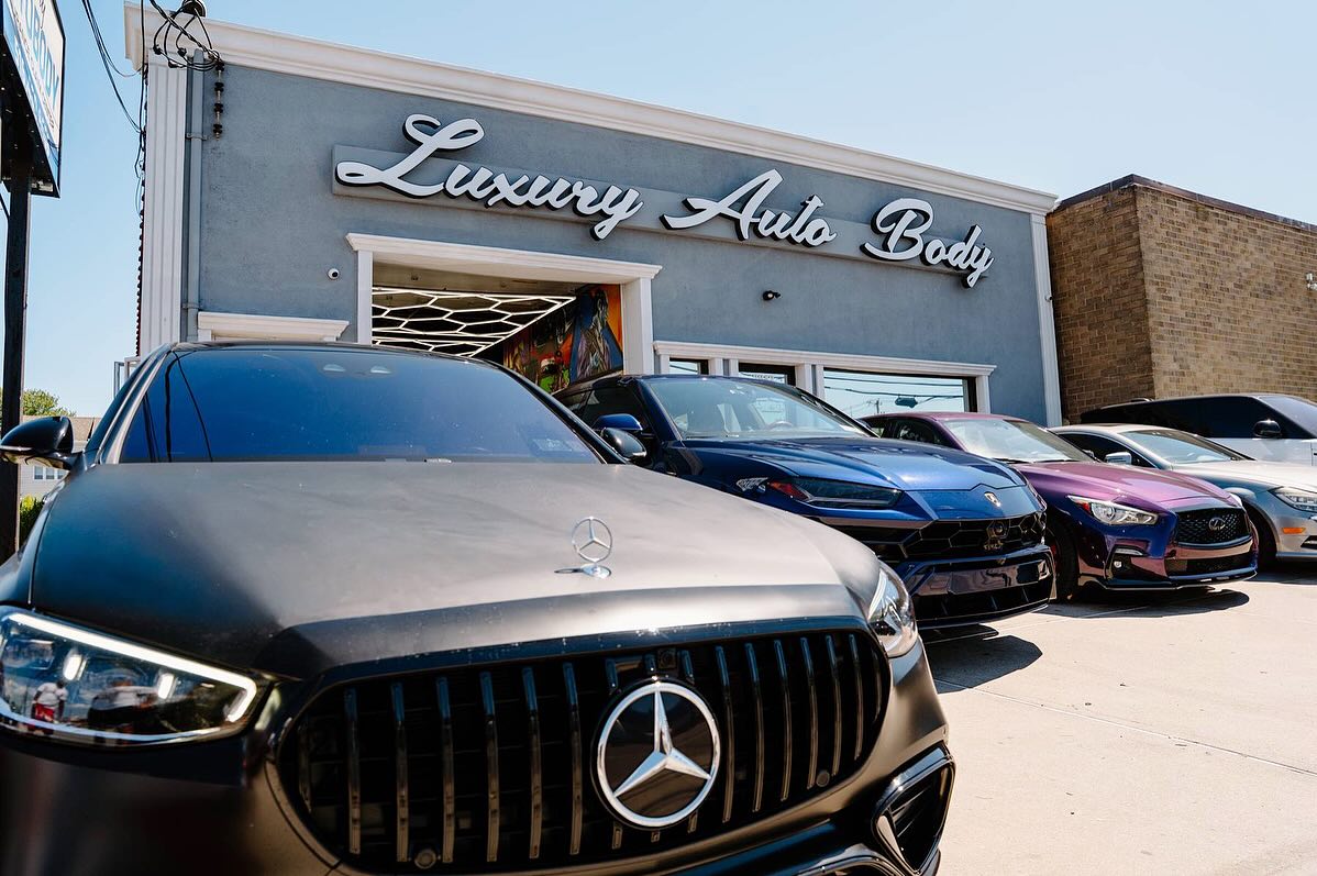 Mercedes, Lamborghini Urus and other luxury cars in front of the Luxury Auto Body shop in Island Park